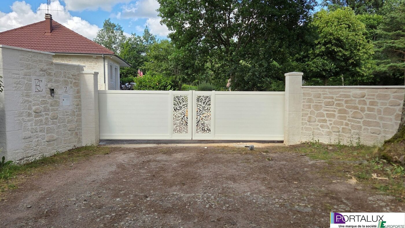 Portail coulissant blanc à motif ajouré, sur piliers en pierre